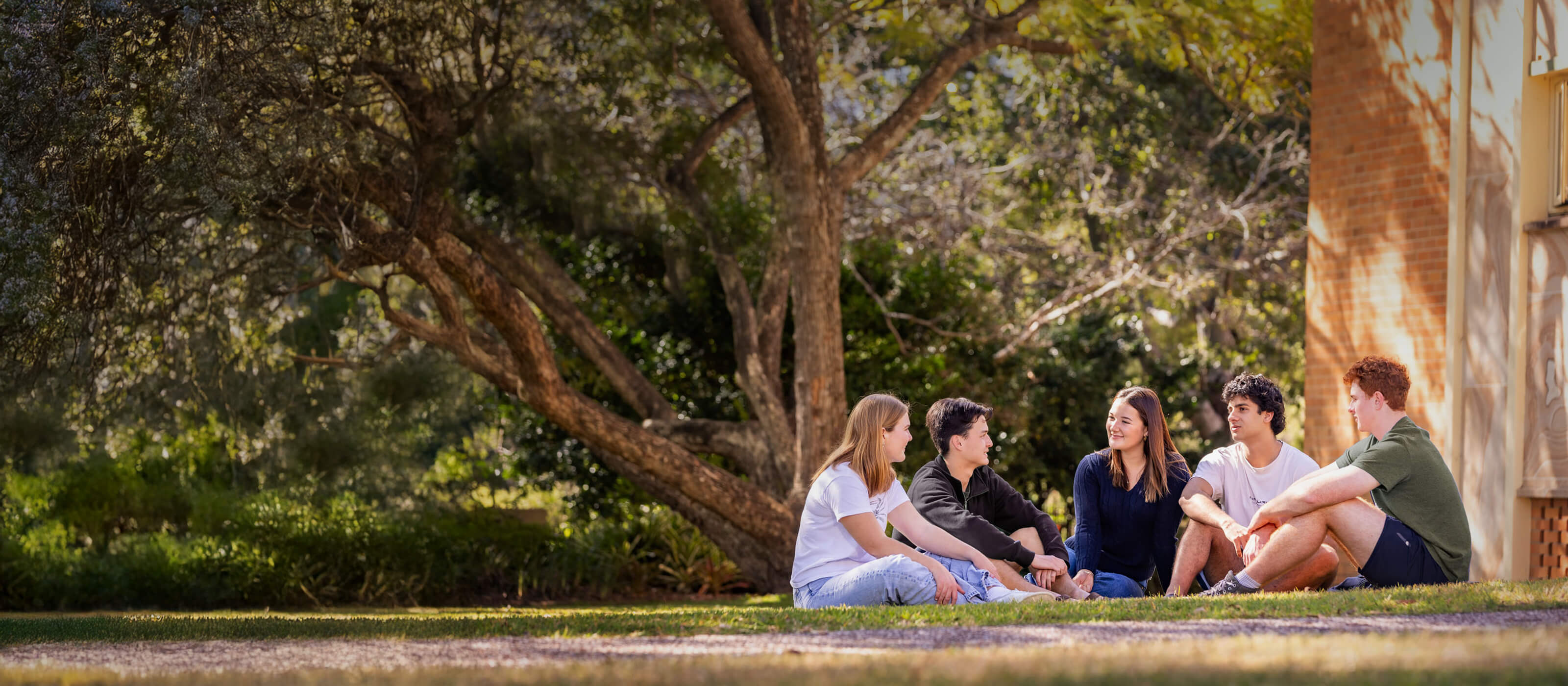 Students relaxing in the campus grounds on a beautiful day engaged laughing and smiling